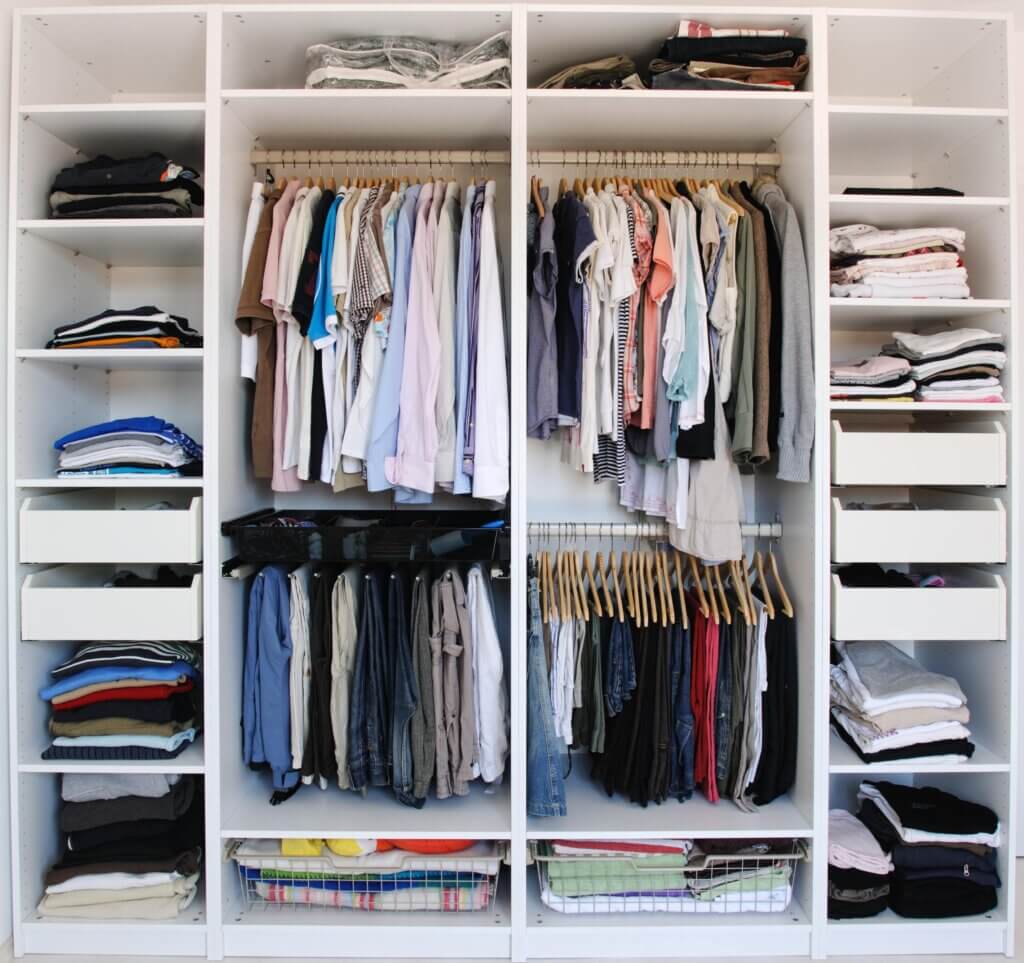 Neatly organized small closet showing clothes, shelves, and storage organizers